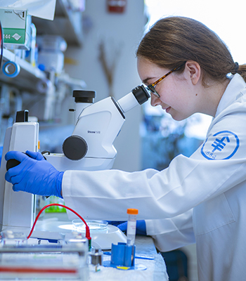 A research scientist at MSK looks into a microscope.