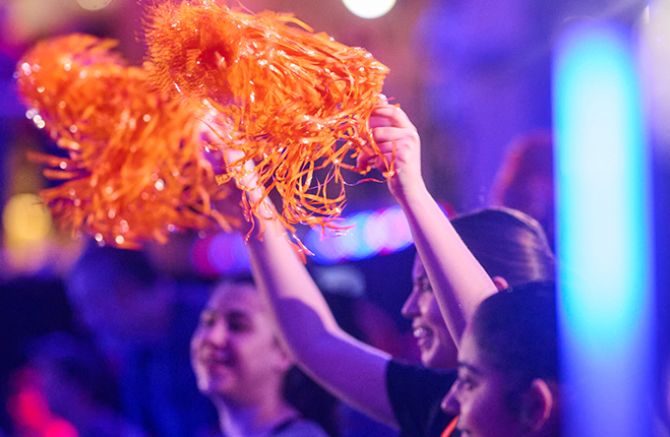 People waving bright orange pom poms at a Cycle for Survival event. 