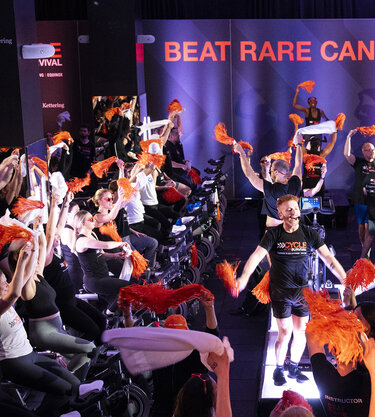 Instructors wearing Cycle for Survival shirts lead a roomful of stationary-bicycle riders at a fundraiser for rare cancer research at MSK.
