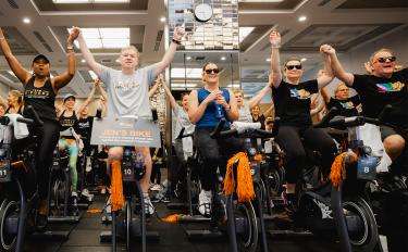 Cycle for Survival participants on stationary bikes celebrate their success raising money for rare cancer research at MSK.