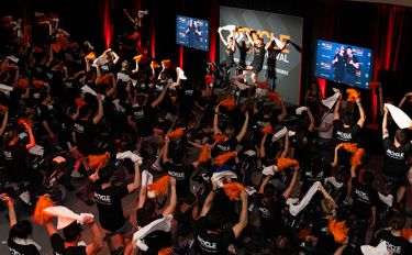 People wearing T-shirts reading “Cycle for Survival” ride stationary bikes at a fundraiser for rare cancer research at MSK.