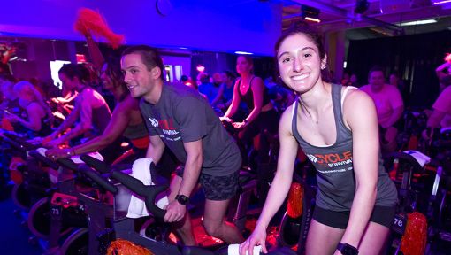People on stationary bikes at a Cycle for Survival rare cancer fundraising event.