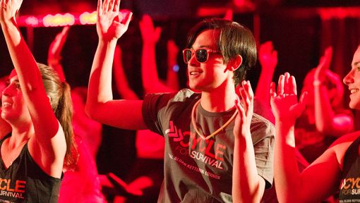 People in workout attire raising their hands, lit by red lighting.