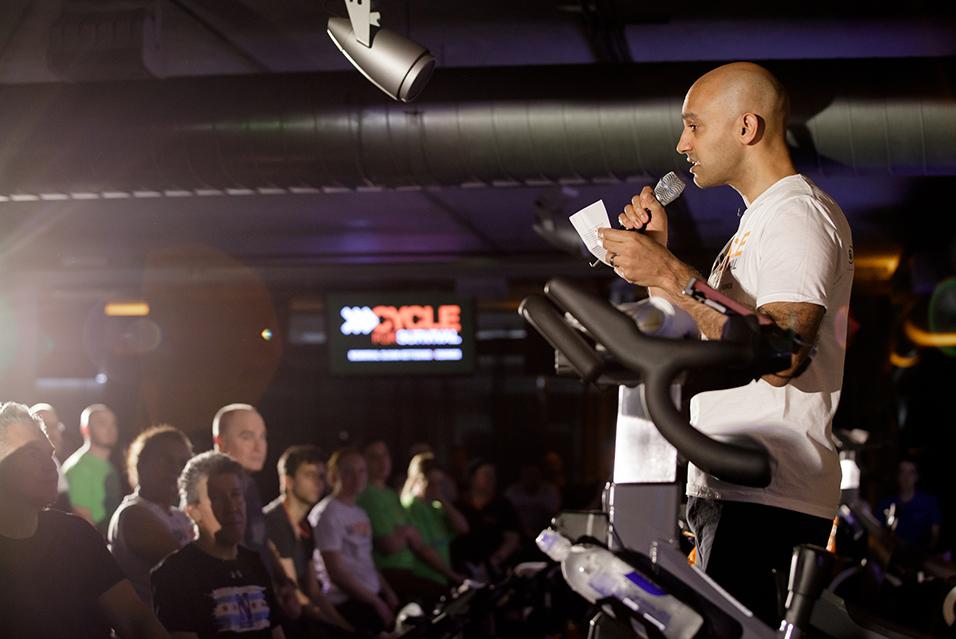 A person standing with a microphone speaking at a Cycle for Survival rare cancer fundraising event in Chicago. 