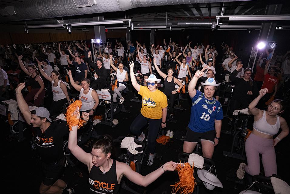 People on stationary bikes at a Cycle for Survival rare cancer fundraising event in Dallas.