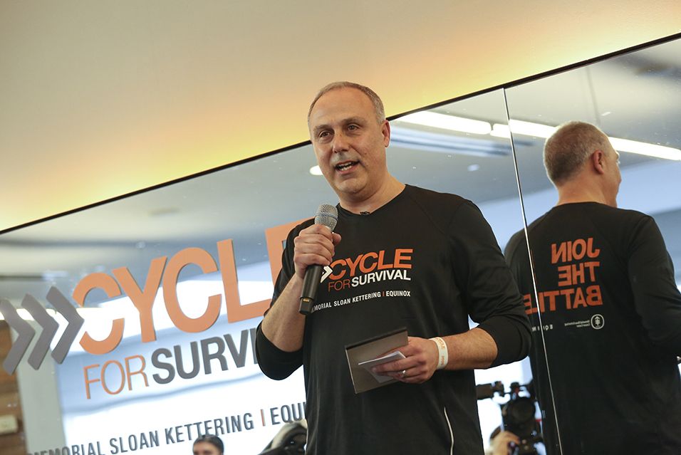 A person standing with a microphone speaking at a Cycle for Survival rare cancer fundraising event in Chicago. 