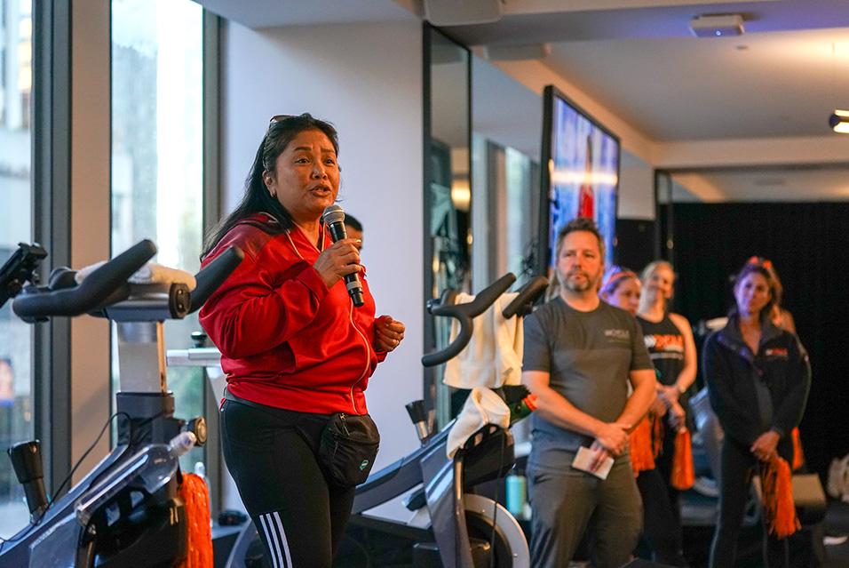 A person standing with a microphone speaking at a Cycle for Survival rare cancer fundraising event in San Francisco. 