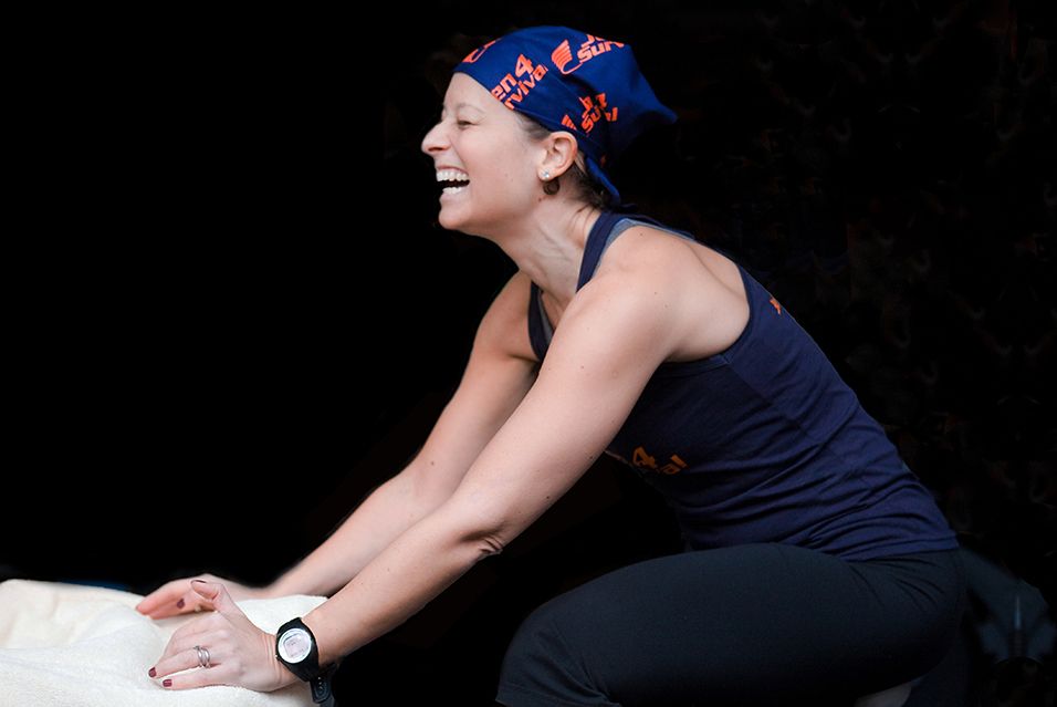 Jennifer Goodman Linn, founder of Cycle for Survival, smiling and laughing as she cycles on a stationary bike. 