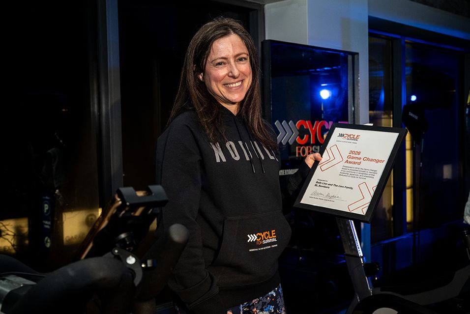 Beth Linn holds a framed 2026 Game Changer Award at a Cycle for Survival event. 