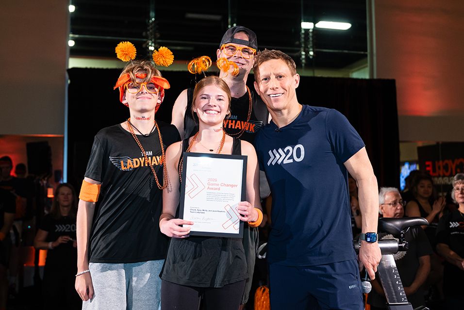 Team Ladyhawk members Chuck, Molly, and Jack Hawkins hold a 2026 Game Changer Award with co-founder Dave Linn at Cycle for Survival. 
