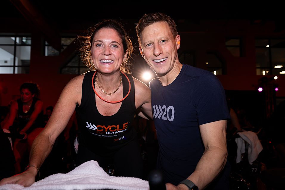 Caitlin Murray, wearing a Cycle for Survival T-shirt, rides next to Dave Linn at a Cycle for Survival fundraising event for rare cancer research at MSK. 