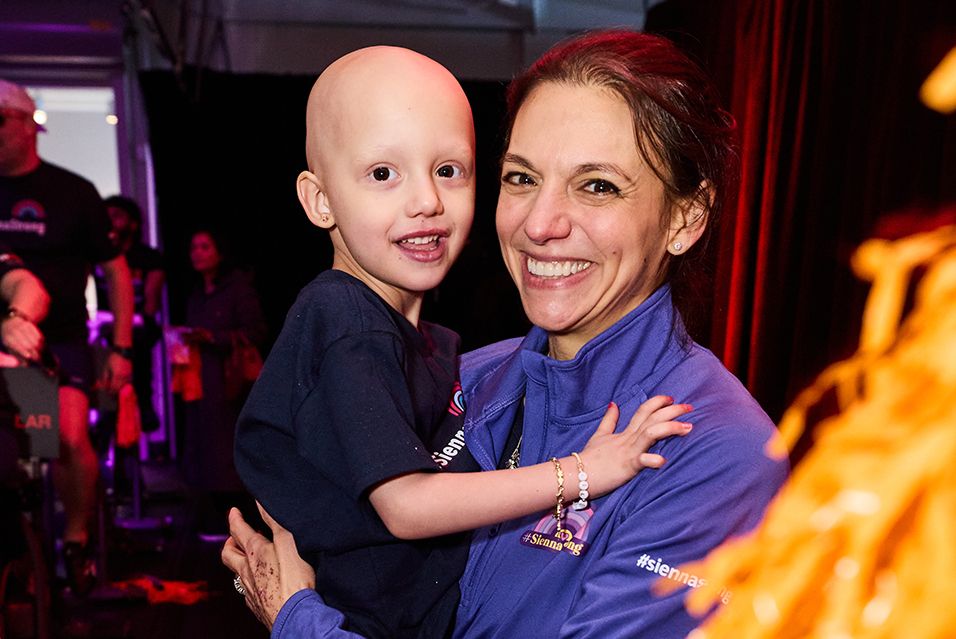 Tara holds her daughter, Sienna, at an indoor event.