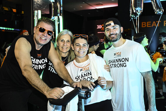 Group smiles at a Cycle for Survival event, wearing "Shannon Strong" shirts.