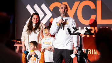 Family on stage with microphones at a Cycle for Survival event.