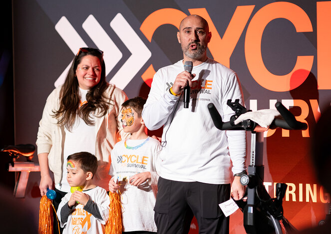 Family on stage with microphones at a Cycle for Survival event.